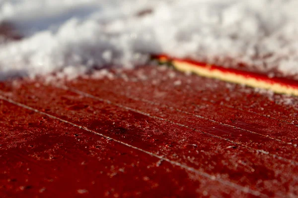 Primeros planos de nieve sobre un fondo rojo de madera — Foto de Stock