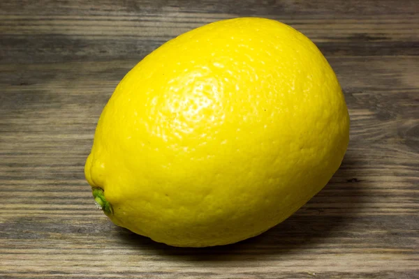 Een gele citroen op houten achtergrond. — Stockfoto