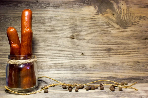 Smoked beer sausage with garlic and spices on wooden background. — Stock Photo, Image