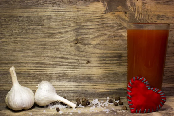 Ein Glas Tomatensaft mit Knoblauch und Gewürzen auf Holzgrund. — Stockfoto