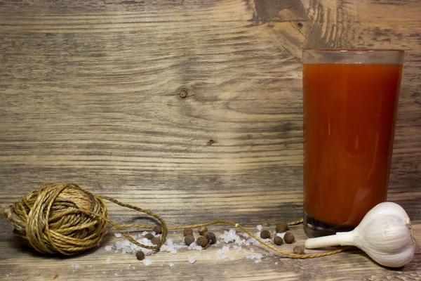 Ein Glas Tomatensaft mit Knoblauch und Gewürzen auf Holzgrund. — Stockfoto