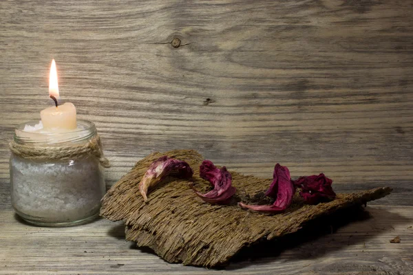 Burning white candle in glass jar on wooden background