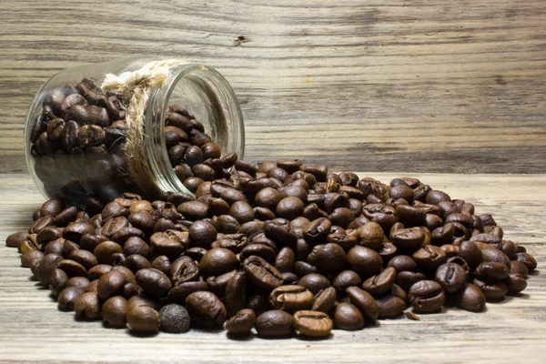 Coffee beans in glass jar on wooden background — Stock Photo, Image