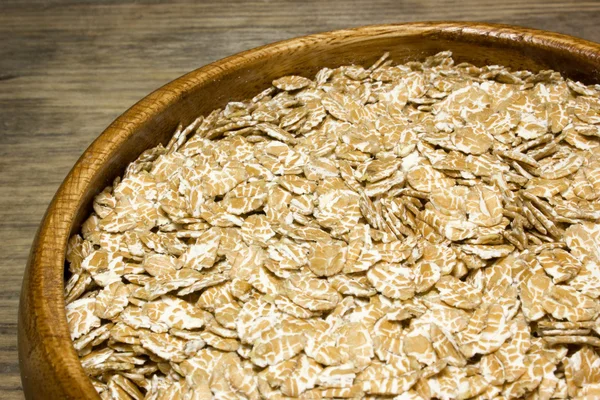 Пшеничні пластівці в дерев'яній тарілці — стокове фото