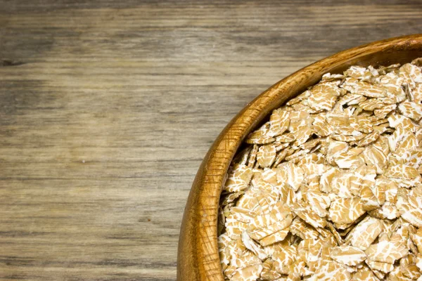 Пшеничні пластівці в дерев'яній тарілці — стокове фото