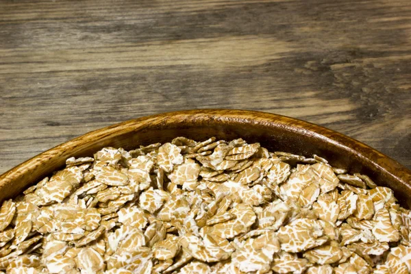 Fiocchi di grano in un piatto di legno — Foto Stock