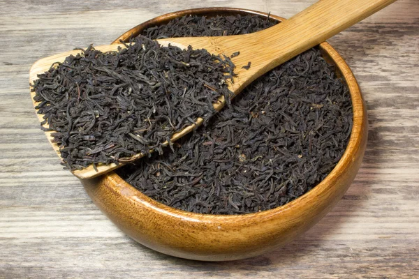 木製の背景にお茶の葉を紅茶の木のスプーン — ストック写真