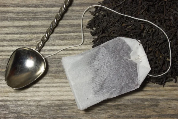 木製の背景にお茶の葉を紅茶と茶紙袋 — ストック写真