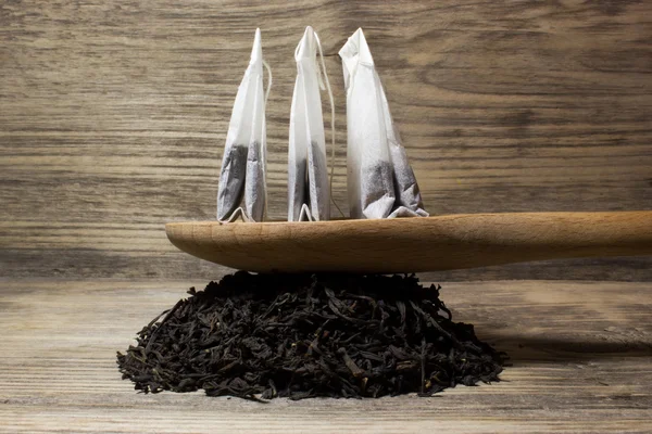 木製の背景にお茶の葉を紅茶と茶紙袋 — ストック写真