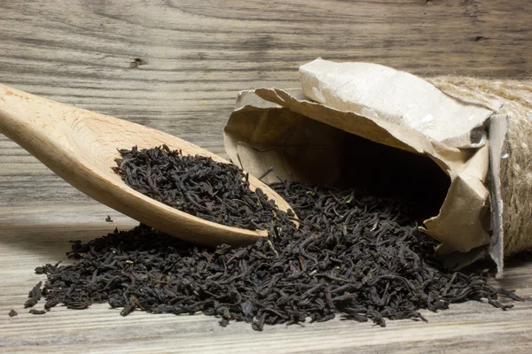 木製の背景にお茶の葉を紅茶の木のスプーン — ストック写真