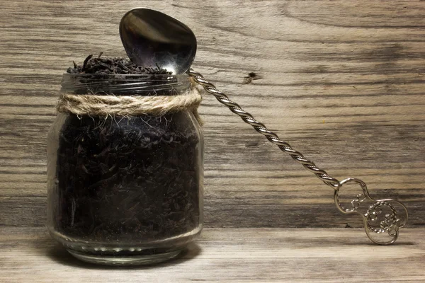 木製の背景に紅茶とガラスの瓶の乾燥茶葉 — ストック写真