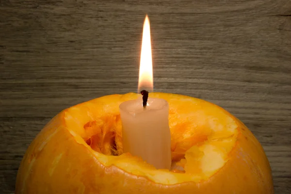 Calabaza amarilla y una vela encendida sobre fondo de madera — Foto de Stock