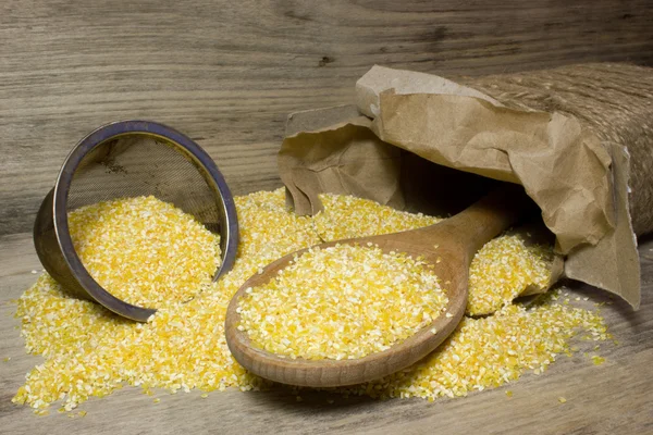 Corn grits and wooden spoon on wooden background