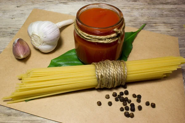 Pasta Espaguetis, ajo, pasta de tomate sobre un fondo de madera — Foto de Stock