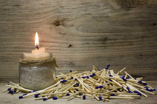 Una vela encendida, Partidos con cabezas azules sobre fondo de madera — Foto de Stock