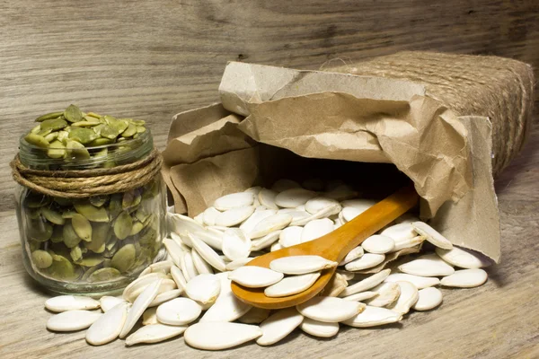 Pumpkin seeds and jar on wooden background — Stock Photo, Image