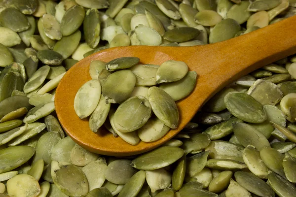 Pumpkin seeds and wooden spoon as background — Stock Photo, Image