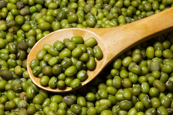 Frijoles mungo verdes y cuchara de madera sobre un fondo de madera — Foto de Stock