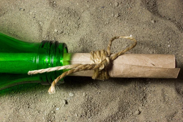 Message in a bottle. A roll of paper in a bottle on the sand.
