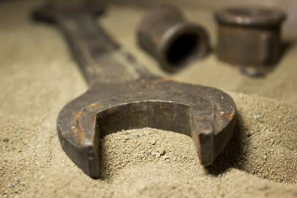 Old wrench and nuts on the sand — Stock Photo, Image