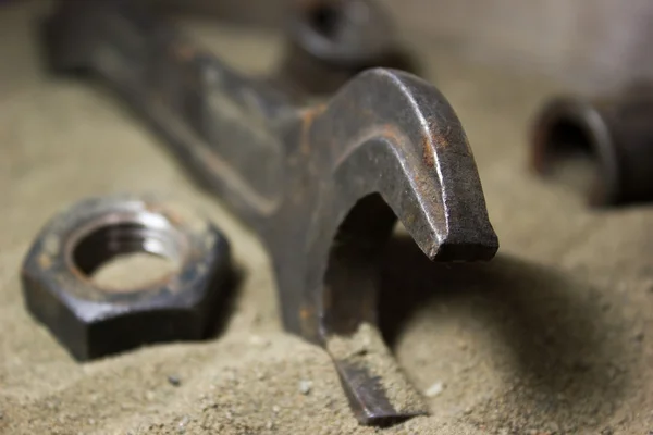 Vecchia chiave inglese e dadi sulla sabbia — Foto Stock