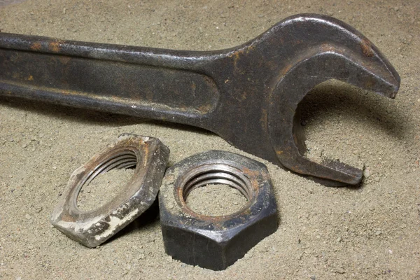 Old wrench and nuts on the sand — Stock Photo, Image