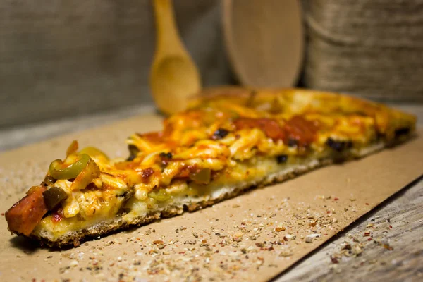 Un pedazo de pizza italiana sobre papel Kraft, utensilios de cocina — Foto de Stock