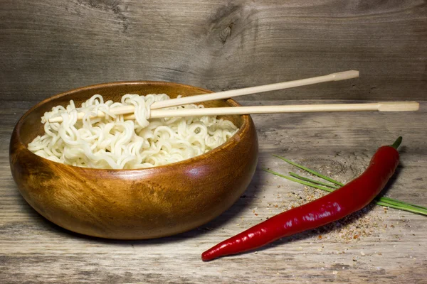 在一个木碗用筷子的方便面。木制的背景和红辣椒. — 图库照片