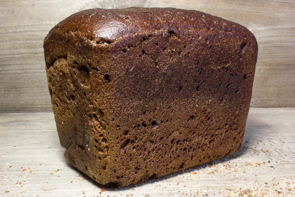 Pan de centeno negro sobre fondo de madera. — Foto de Stock