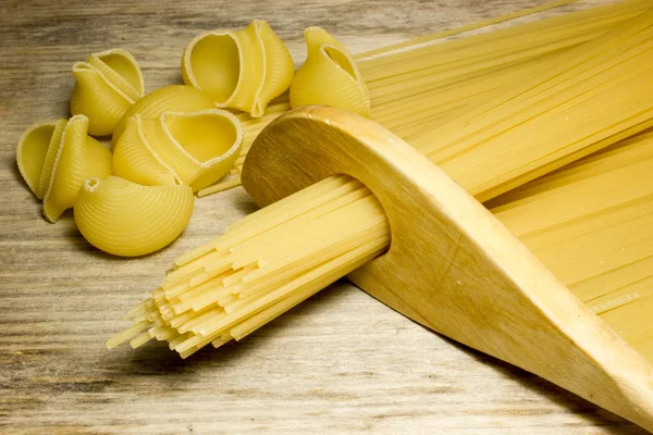 Espaguetis y cuchara de madera sobre fondo de madera — Foto de Stock