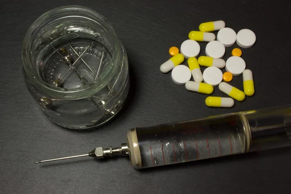 Медицинский шприц и таблетки на тёмном фоне — стоковое фото