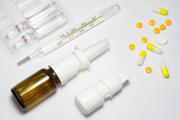 Termômetro médico e pílulas em fundo branco — Fotografia de Stock