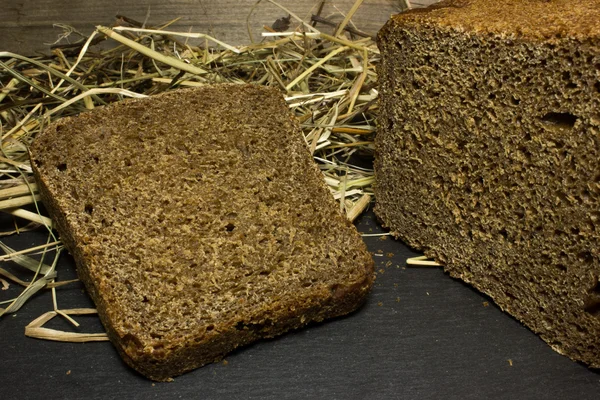 Pan de centeno negro en el fondo del heno — Foto de Stock