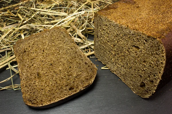 Pan de centeno negro en el fondo del heno — Foto de Stock