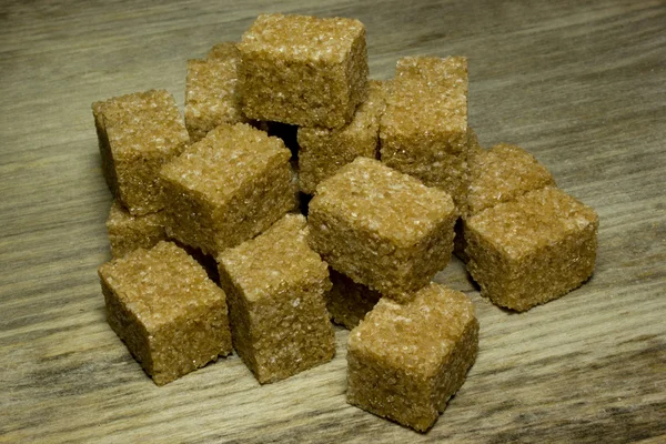 Cubos de azúcar de caña marrón sobre fondo de madera —  Fotos de Stock