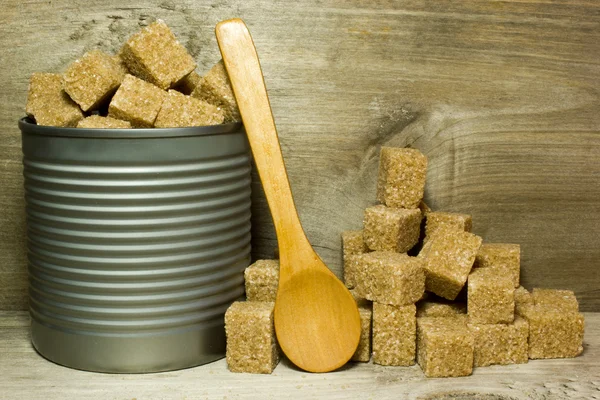 Cubes brown cane sugar and spoon on wooden background