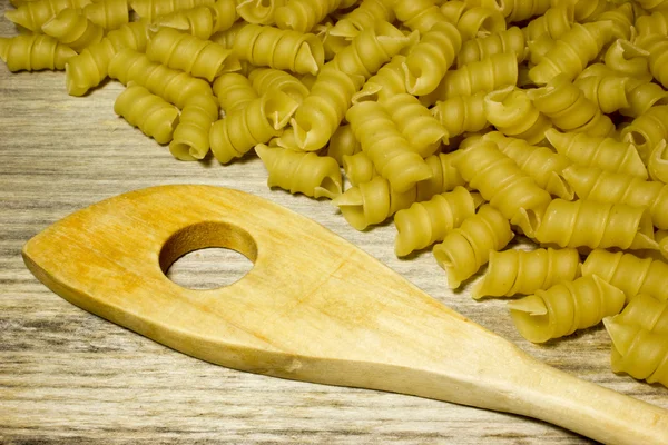 Tagliatelle a spirale e cucchiaio su sfondo di legno — Foto Stock