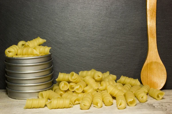 Tagliatelle a spirale e cucchiaio su sfondo di legno — Foto Stock