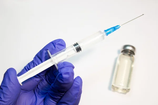 A seringa na mão e ampola sobre um fundo branco — Fotografia de Stock