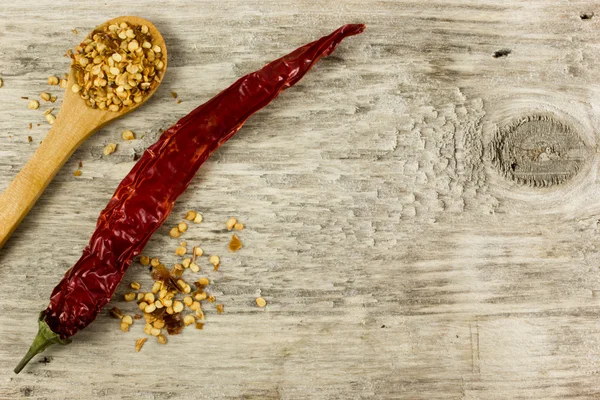 Chilipeper en zaden op houten tafel — Stockfoto