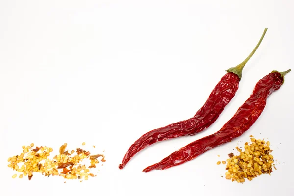Chili papričky a semena v dřevěnou lžící na bílém pozadí — Stock fotografie