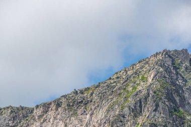 Mavi bulutlu gökyüzünün altında ufukta kayalık bir tepe var. Yolculuk için dağ vadisi. Macera seyahati, turizm ve koruma kavramı.