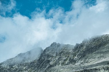 Mavi gökyüzü ve kayaların üzerindeki bulutlar, dağların üzerindeki güzel bulut manzarası.