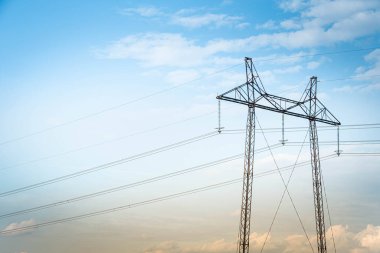 Gökyüzüne ve bulutlara karşı güç hattı kulesi. Enerji şirketinden elektrik aktarımı. Yüksek voltaj sütunları ve çizgileri olan manzara.