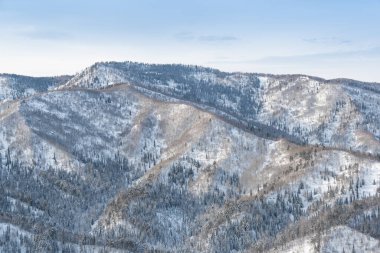 Orman tepelerinin yumuşak yamaçları ilk karla kaplıdır. Ufuktaki dağ vadileri ve tepe manzarası.