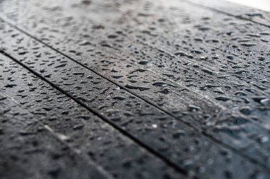 Su, ahşap masanın siyah yüzeyine düşer.