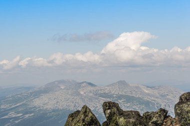 Mavi bulutlu gökyüzünün altında ufukta kayalık bir tepe var. Yolculuk için dağ vadisi. Macera seyahati, turizm ve koruma kavramı.