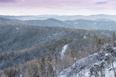 Orman tepelerinin yumuşak yamaçları ilk karla kaplıdır. Ufuktaki dağ vadileri ve tepe manzarası.