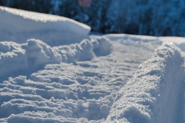 Derin karda kar motosikleti izleri. Karla kaplı bir araziyi geçen bir kar aracının çarpık izleri.