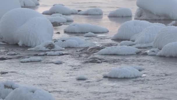 Камни в холодной воде покрыты снегом — стоковое видео